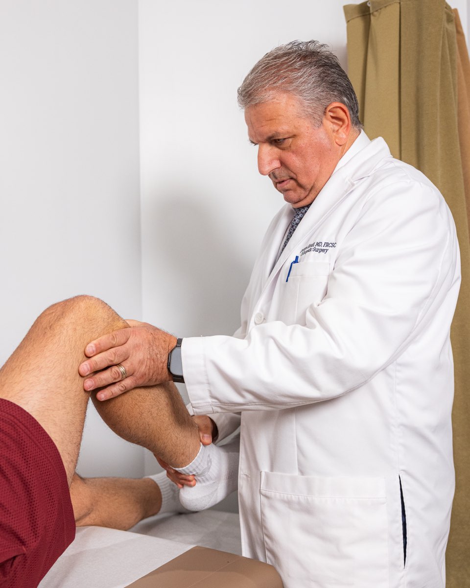 Dr. Georges Sioufi examining a patient's knee